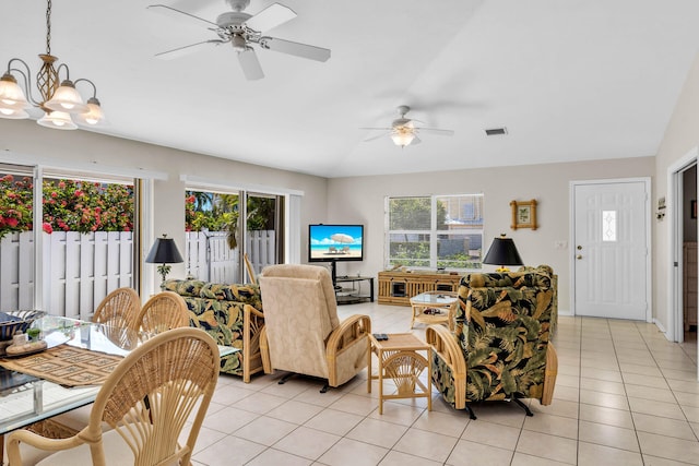 living area featuring ceiling fan with notable chandelier, light tile patterned flooring, visible vents, and baseboards