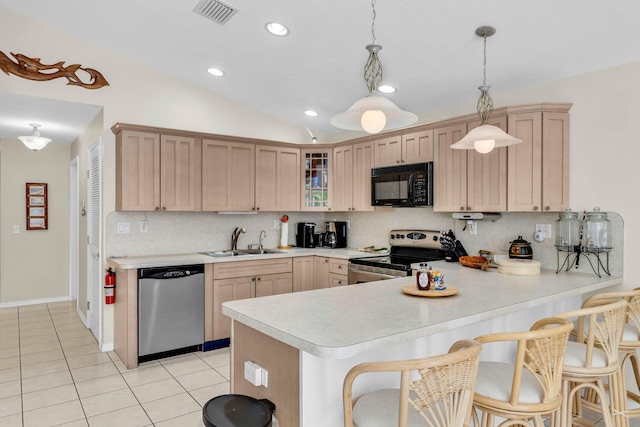 kitchen featuring glass insert cabinets, appliances with stainless steel finishes, a peninsula, light countertops, and a sink