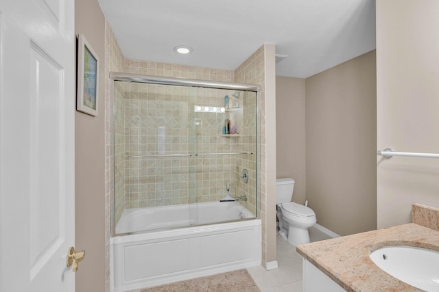 bathroom with toilet, enclosed tub / shower combo, vanity, tile patterned flooring, and baseboards