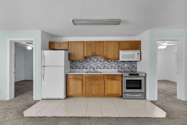 kitchen featuring light colored carpet, white appliances, a sink, light countertops, and brown cabinetry