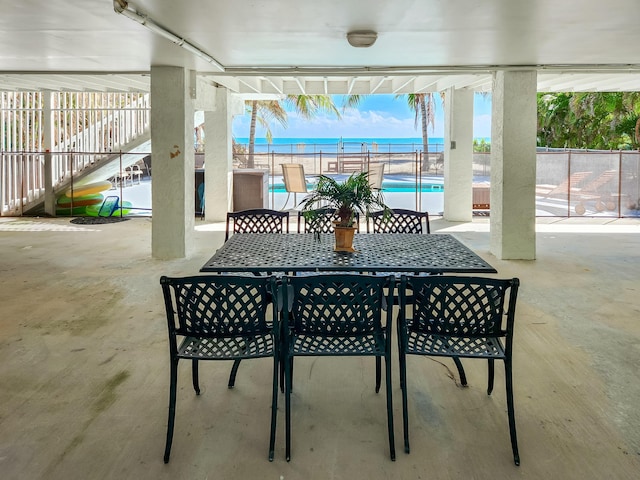 view of patio / terrace with stairway, fence, a water view, outdoor dining area, and a community pool