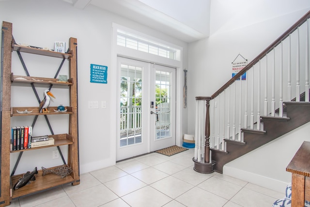 foyer with tile patterned floors, a towering ceiling, stairs, and french doors