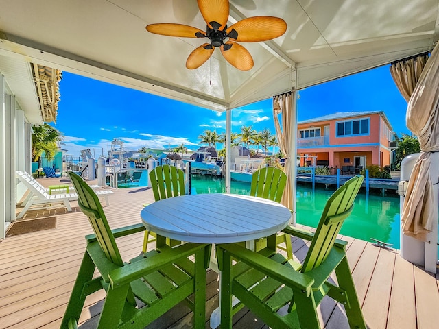 deck with a dock, a water view, and a ceiling fan