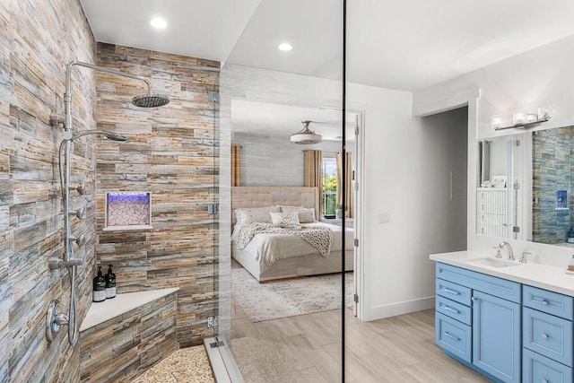 ensuite bathroom featuring recessed lighting, tiled shower, and vanity