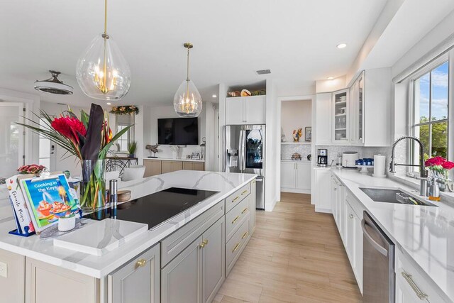 kitchen featuring white cabinets, a sink, stainless steel appliances, backsplash, and glass insert cabinets