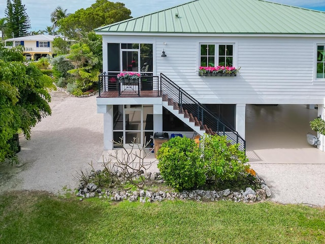 back of house featuring metal roof, stairs, a patio area, and a carport