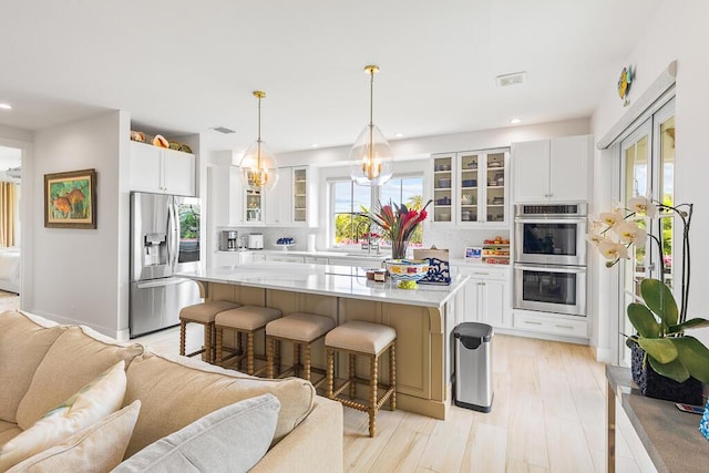 kitchen with light countertops, open floor plan, appliances with stainless steel finishes, and plenty of natural light