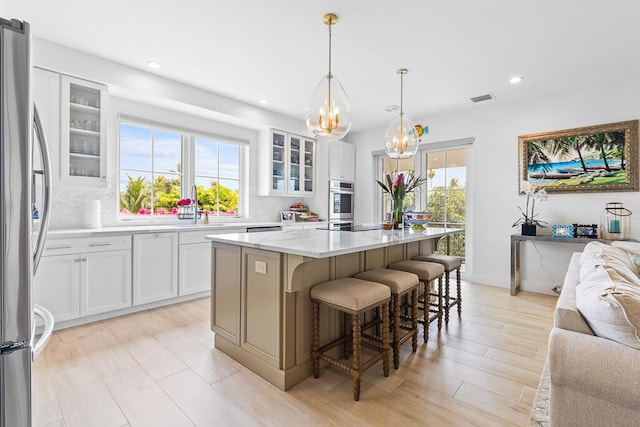 kitchen with an inviting chandelier, visible vents, freestanding refrigerator, and a wealth of natural light