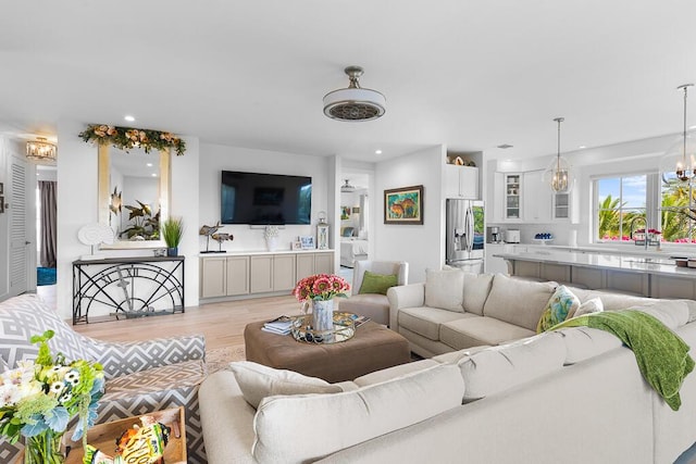 living area with light wood finished floors, recessed lighting, and a chandelier
