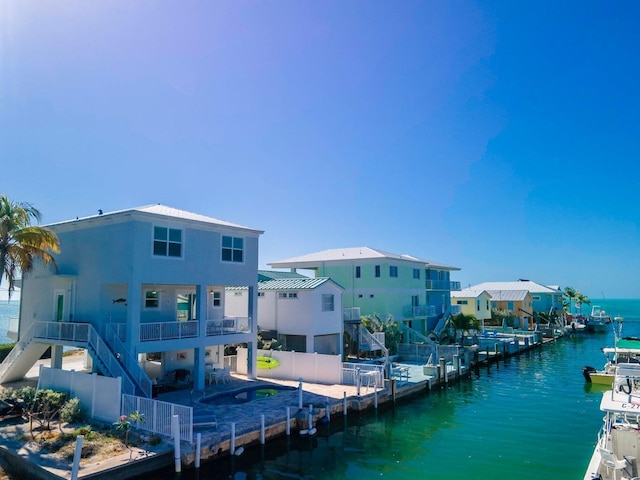 rear view of house featuring a water view, a patio area, a fenced backyard, and stairway