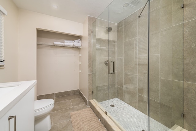 full bath with toilet, a stall shower, vanity, and tile patterned floors