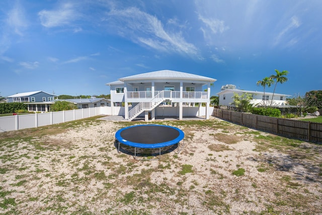 back of house featuring ceiling fan, a trampoline, stairway, and a fenced backyard