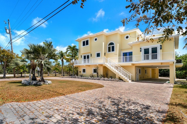 view of building exterior featuring a carport, decorative driveway, and stairs
