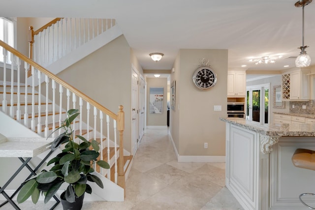 hallway featuring light tile patterned flooring, baseboards, and stairs