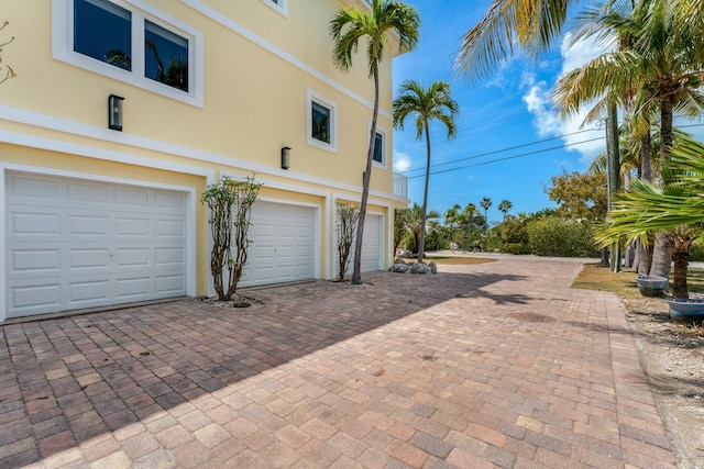 view of home's exterior featuring a garage, decorative driveway, and stucco siding