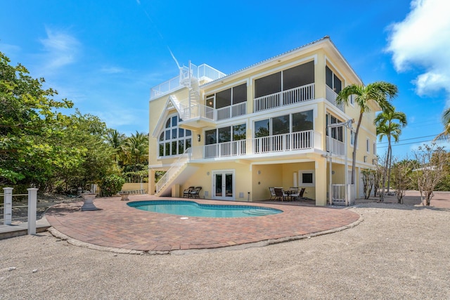 back of house with stucco siding, a patio, stairs, an outdoor pool, and french doors