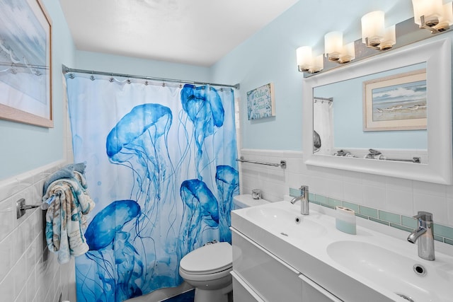 full bathroom with a wainscoted wall, toilet, tile walls, and a sink