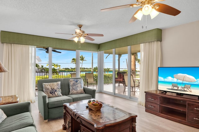 living room featuring a ceiling fan, a healthy amount of sunlight, light wood-style flooring, and a textured ceiling