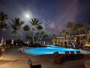 pool at twilight featuring a patio and a community pool