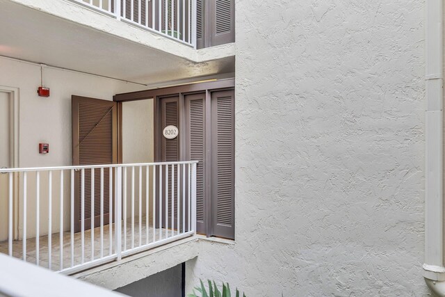 view of exterior entry featuring a balcony and stucco siding