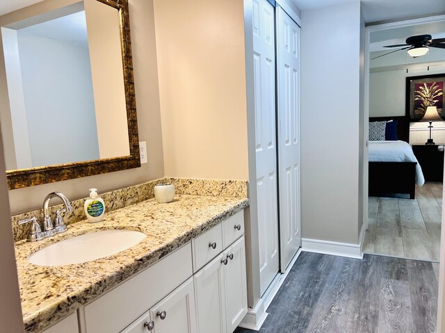 ensuite bathroom featuring a closet, ceiling fan, vanity, ensuite bath, and wood finished floors