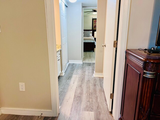 hall with baseboards and light wood-style floors