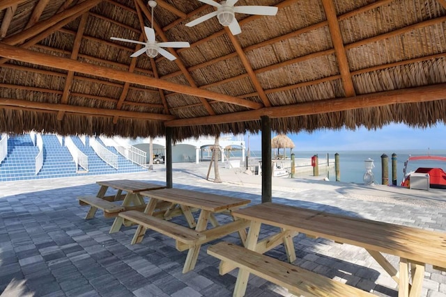 view of patio featuring a ceiling fan, a water view, and a gazebo