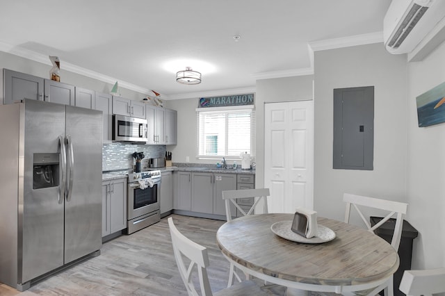 kitchen with electric panel, ornamental molding, appliances with stainless steel finishes, a wall mounted air conditioner, and gray cabinets