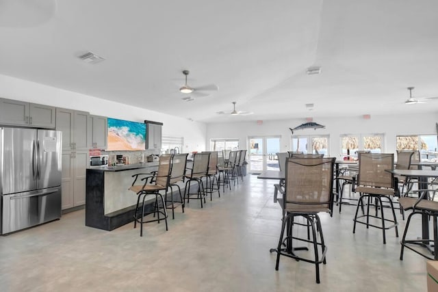 kitchen with appliances with stainless steel finishes, a breakfast bar area, visible vents, and tasteful backsplash