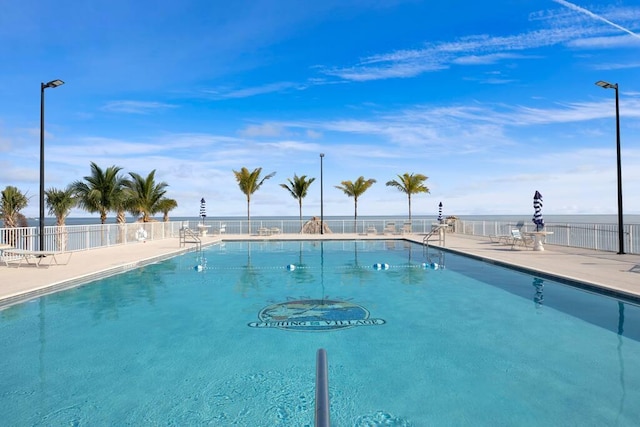 community pool with a patio area and fence