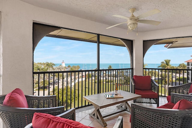 balcony featuring a ceiling fan, a sunroom, and a water view