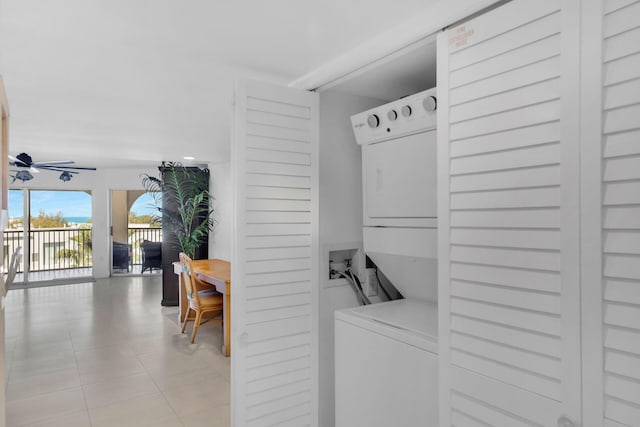 laundry area featuring stacked washer / drying machine, laundry area, ceiling fan, and light tile patterned floors