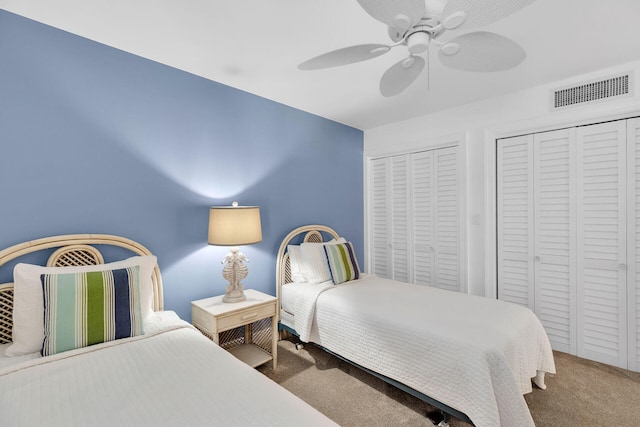 bedroom featuring ceiling fan, carpet flooring, visible vents, and multiple closets