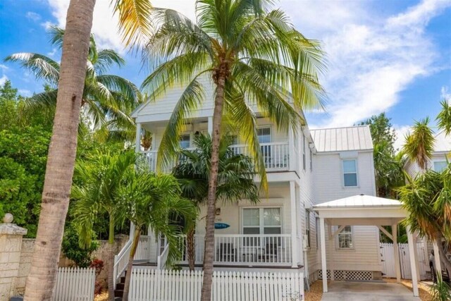 7202 Simran Ln, Duck, FL 33050 - view of front facade with a balcony, a fenced front yard, a metal roof, a gate, and covered porch