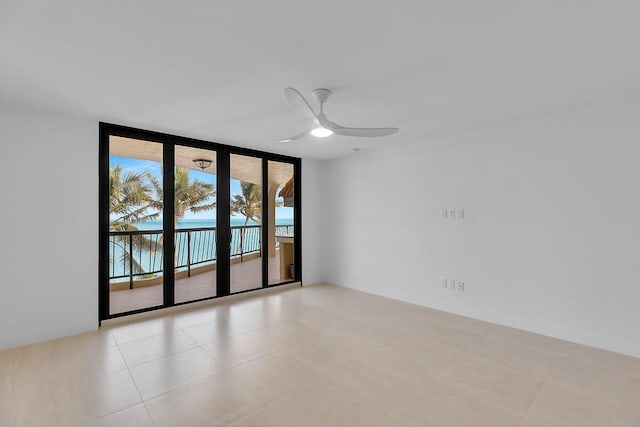 empty room with a ceiling fan and a wall of windows