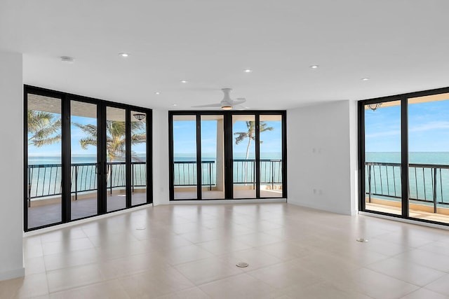 empty room with a ceiling fan, a wall of windows, and plenty of natural light