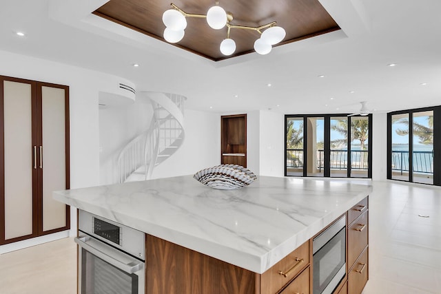 kitchen with a raised ceiling, modern cabinets, floor to ceiling windows, open floor plan, and appliances with stainless steel finishes