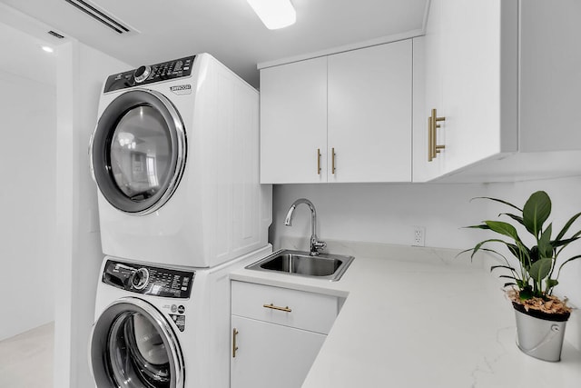 clothes washing area featuring stacked washer / drying machine, a sink, and cabinet space