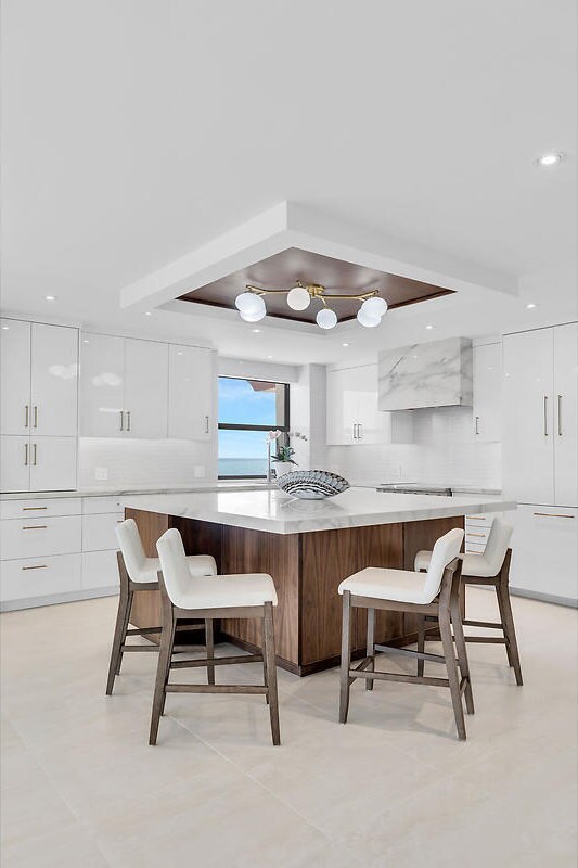 kitchen featuring modern cabinets, a tray ceiling, tasteful backsplash, white cabinetry, and a breakfast bar