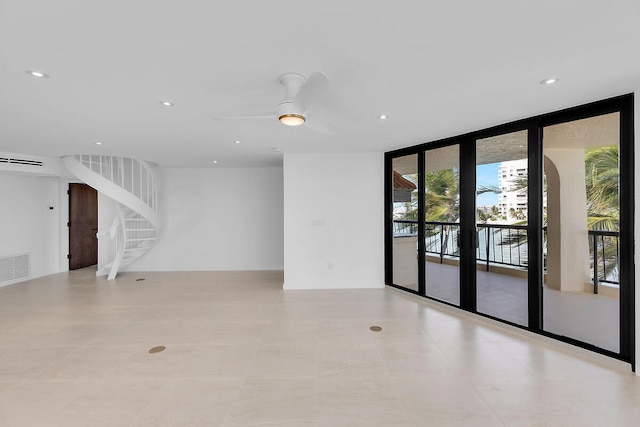 unfurnished room with floor to ceiling windows, a ceiling fan, visible vents, stairway, and recessed lighting