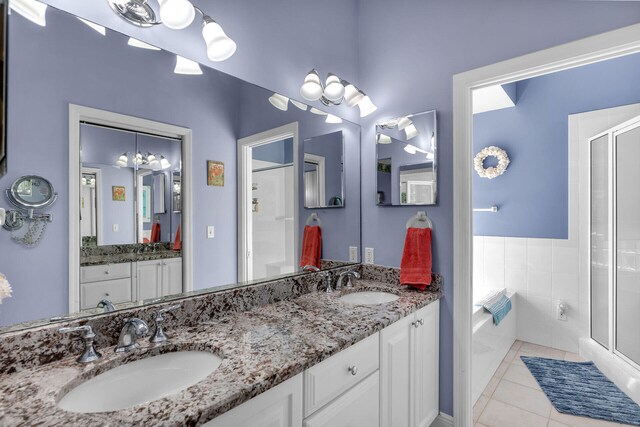 bathroom featuring a bath, a shower stall, double vanity, and a sink