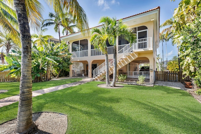 exterior space with stucco siding, a lawn, stairway, a sunroom, and fence