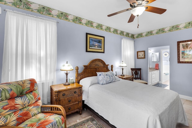 bedroom featuring light tile patterned floors, baseboards, and ensuite bathroom