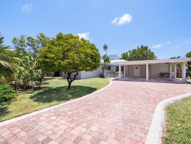 ranch-style home featuring a front lawn, decorative driveway, and a carport