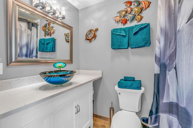 full bathroom with toilet, a shower with curtain, baseboards, and vanity