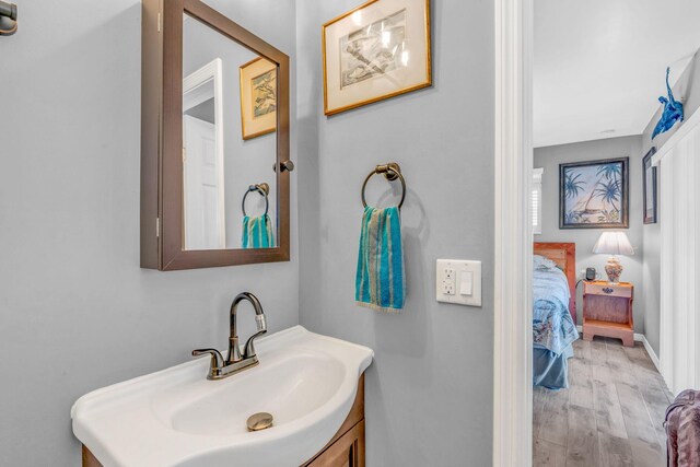 bathroom with connected bathroom, vanity, baseboards, and wood finished floors