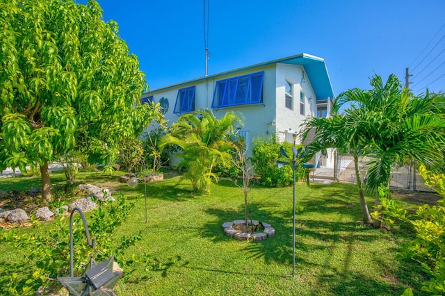 exterior space featuring a lawn, fence, a gate, and stucco siding