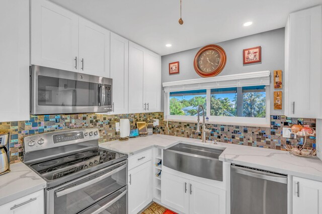 kitchen with appliances with stainless steel finishes, a sink, and white cabinets