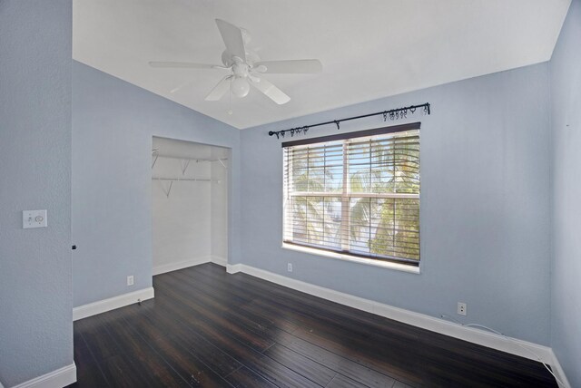 unfurnished bedroom with vaulted ceiling, dark wood-style flooring, a closet, and baseboards