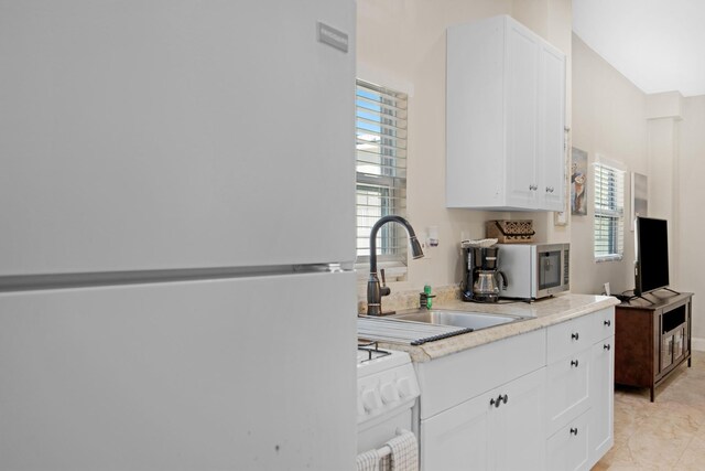 kitchen featuring light countertops, white appliances, a sink, and white cabinets